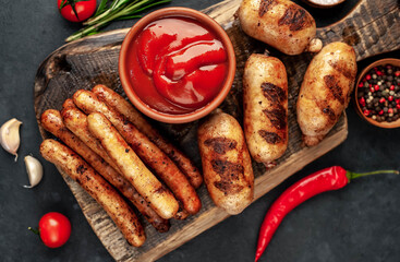 Different grilled sausages with spices and
rosemary, served on a cutting board on a stone background