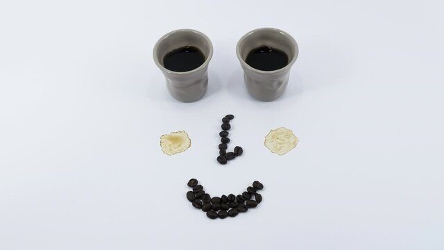 Zurich, Switzerland - June 12, 2020: As two coffee cups fills with coffee, cheeks are getting expression, hair grow, eyes move through milk addition. Animated stop motion.