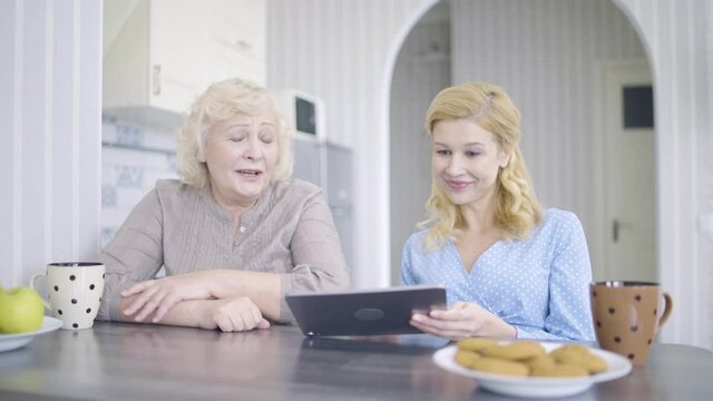 Happy young woman and mother watching photos on tablet, buying clothes online