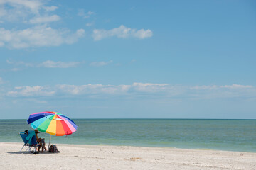 Vacationers Relaxing Under a Colorful Umbrella on the Gulf Coast at Sanibel Island Florida