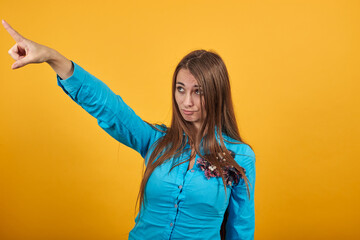 Hand pointer with forefinger pointing forward. Index finger to show direction. Means choosing, introducing too. Indicating towards. Attractive woman with brown hair, eyes, decoration on blue shirt