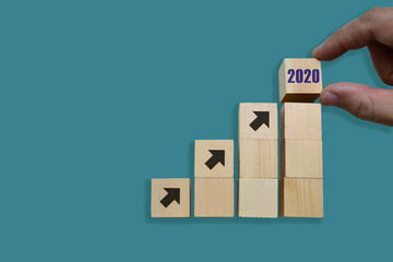 Business concept growth 2020 success process, Close up man hand arranging wood block stacking as step stair on blue background, copy space.