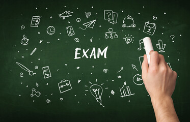 Hand drawing EXAM inscription with white chalk on blackboard, education concept