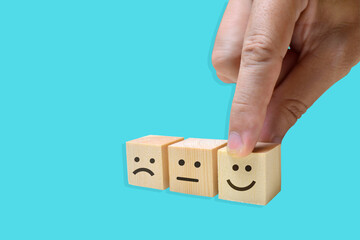 Close up customer hand choose smiley face icon on wood cube, Service rating, satisfaction concept.