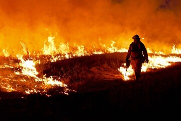 Firefighter starts fire with drip torch.