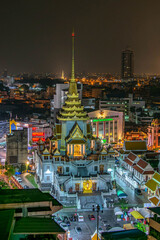 Illuminated buddhist temple, city lights and buildings by night