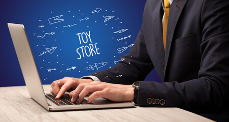 Businessman working on laptop with TOY STORE inscription, online shopping concept