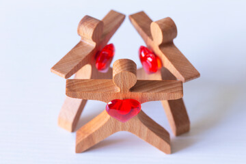 Love triangle concept. Wooden figures with red hearts form a triangle.