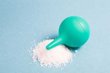 small green rubber enema with a handful of sea salt on a light blue background, copy space, rinsing...