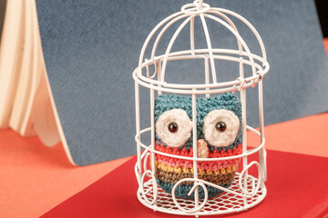 Homemade knitted owl in a metal cage for birds