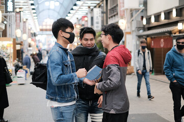Group of young asian friends talking about the trip to travel on walking street while open the map