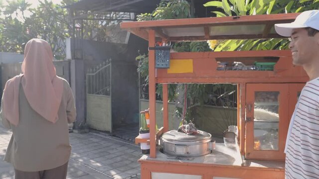 street food vendor handing a bowl of bakso or meatball to customer