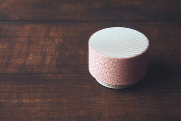 Portable wireless speaker isolated on wooden table