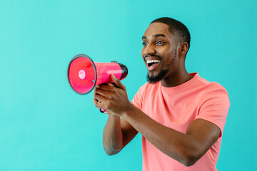 Portrait of a positive young man speaking through megaphone with mouth open