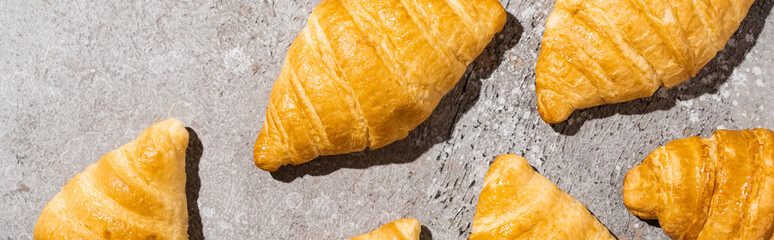 top view of fresh baked croissants on concrete grey surface, panoramic shot