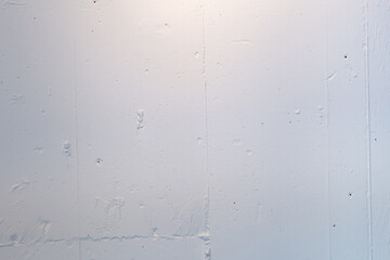 白くペイントされた質感のあるコンクリートの壁