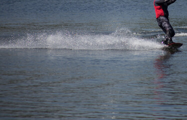 The man does wakeboarding on the water in the summer in a helmet and wetsuit.