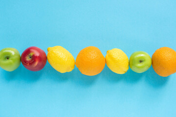 top view of ripe fruits in line on blue background