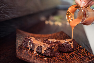 Caramel brownie dessert bars on rustic dark background