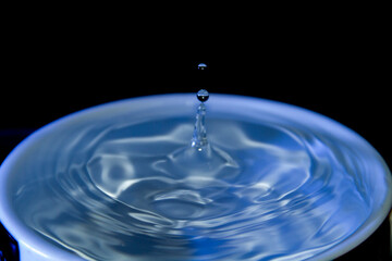 Water drop falling on a cup full with water
