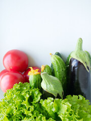 Set of seasonal vegetables: fresh salad, farm cucumbers, red tomatoes and eggplant below, on a light background. copy space. Farm vegetables, comfortable digestion. Proper nutrition, weight loss. 