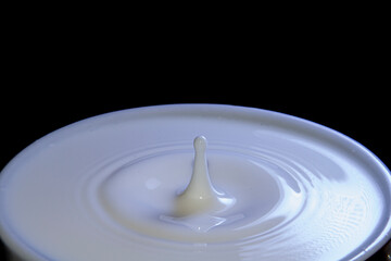 Milk drop falling on a cup full of milk