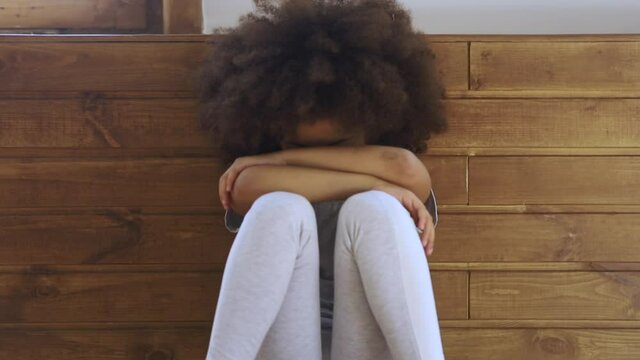 Upset little african american preschool kid girl crying alone feeling bullied abused abandoned, sad offended lonely black orphan child stressed or scared sitting on floor, children problems concept