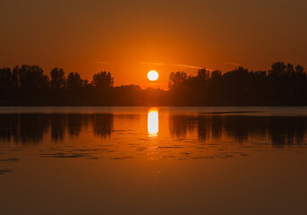 Dramatic sunset on a lake with tree reflection