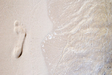 Footprint in the sand with pure water and little waves