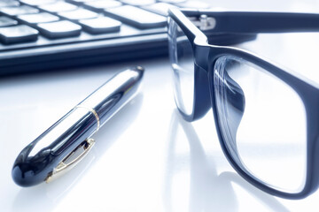 Stylish black business glasses, pen and calculator on white