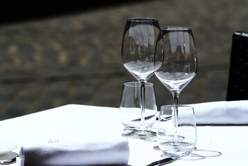 Transparent glasses on the table of an outdoor restaurant, white tablecloth, daylight.