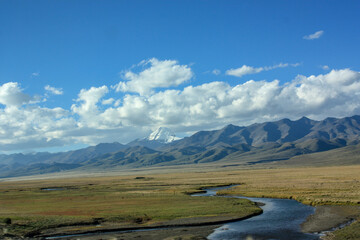 First view on Kailash Mountain rising from Barkha plain from the road from the distance with fields in front with river