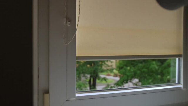 woman opens blackout roller blinds.  Window in the Interior with roller jalousie. yellow louvres on the window.
