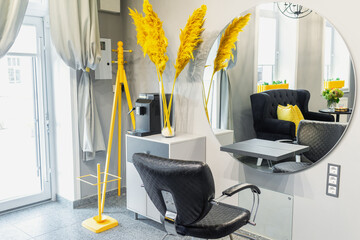 Interior of modern beauty and hairdresser salon with armchair and mirror in yellow and black tones.