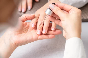  Professional manicurist pouring oil on nails french manicure of woman in beauty salon. © okskukuruza