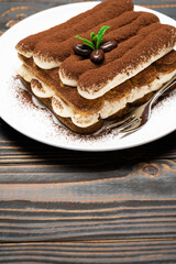 Classic tiramisu dessert on ceramic plate on wooden background