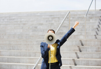 Businesswoman using megaphone on urban steps
