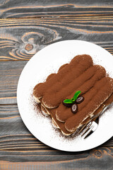 Classic tiramisu dessert on ceramic plate on wooden background