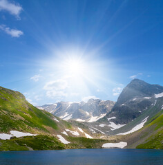 small lake in a green mountain valley under a sparkle sun