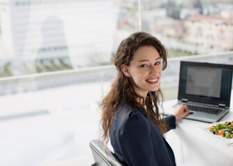 Portrait of smiling businesswoman using laptop and eating lunch