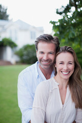 Obraz premium Portrait of smiling couple in yard with house in background