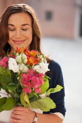 Fototapeta premium Smiling woman smelling bouquet of flowers