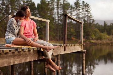 Serene couple sitting at edge of dock over lake