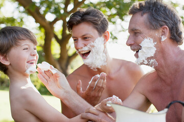 Playful multi-generation men applying shaving cream to faces