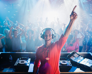 Portrait of enthusiastic DJ with arm raised people on dance floor  - obrazy, fototapety, plakaty