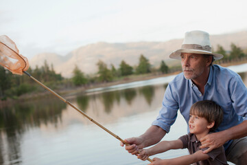 Grandfather and grandson fishing at lake