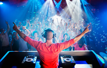 DJ with arms outstretched overlooking dance floor