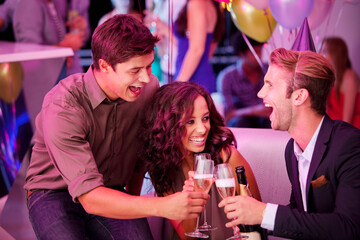 Enthusiastic friends toasting champagne flutes in nightclub