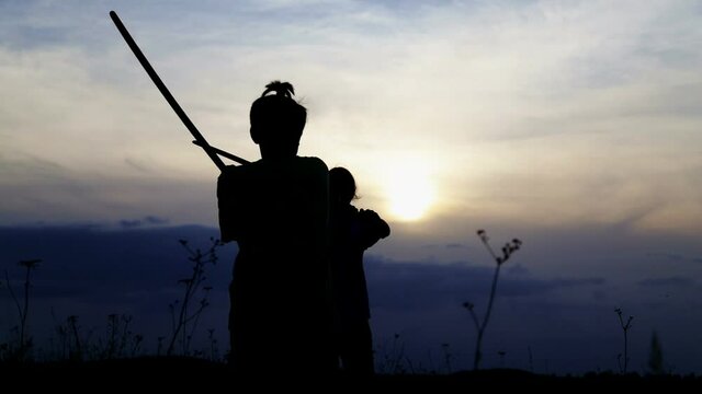Teenage boys fencing with samurai training swords. Silhouette of exercising children in a field with swords.