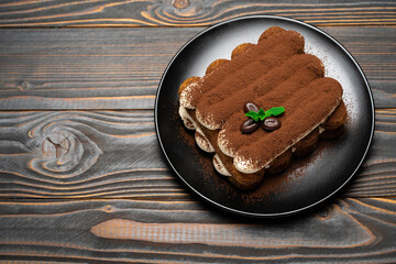 Classic tiramisu dessert on ceramic plate on wooden background